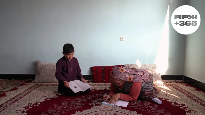 Une femme et un garçon assis sur un tapis écrivent et lisent, dans une pièce lumineuse et chaleureuse.